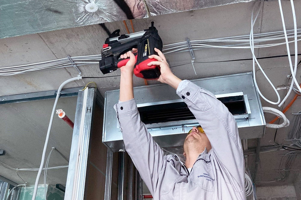 Bauarbeiter hält FORCE ONE bei der Überkopfmontage an Betondecke