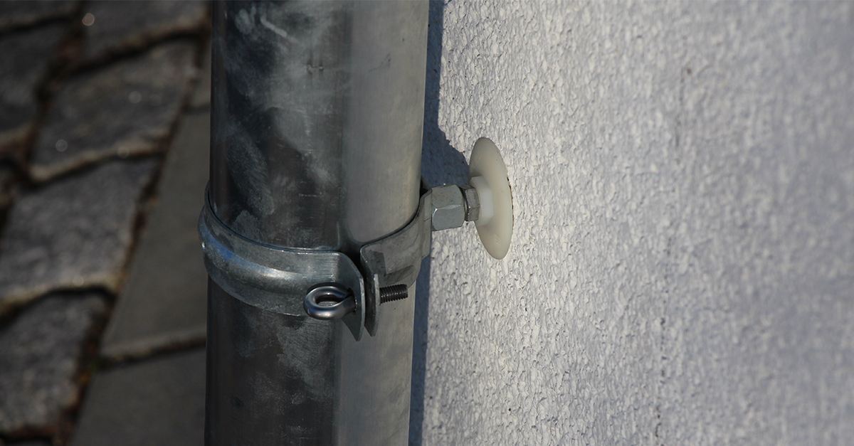 Isolationsdübel IPL 95 DS an der verputzten Fassade hält eine Regenfallrohrschelle